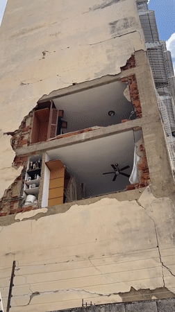 Caracas apartment building shows major facade damage with equipment on site