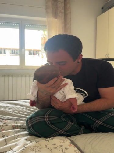 Father tenderly holds newborn baby in Aprilia, Italy
