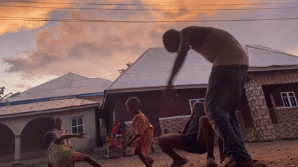 Children play in dirt yard during sunset in Achara