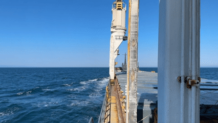 Ship navigates choppy seas with mountains visible on horizon