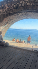 Couple sits under stone archway overlooking Rijeka beach