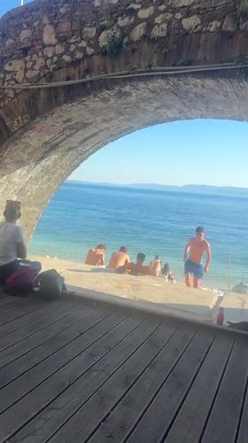 Couple sits under stone archway overlooking Rijeka beach