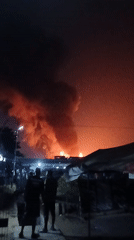 Large fire draws onlookers as smoke billows across night sky