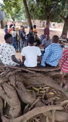 Outdoor community gathering under the trees in Akwanga
