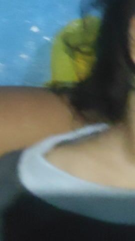 The media file contains a close-up shot of a young child's face, viewed from the side. The child appears to be sleeping or resting, with their eyes closed and their head tilted. A hand is visible near the child's mouth, potentially holding or comforting them. The background is blurred, but hints of a green patterned fabric, possibly a blanket or clothing, are discernible. There are also abstract shapes and colors in the background, including what might be a table or surface with some objects on it, suggesting an indoor setting. The lighting is soft, and the overall mood seems peaceful and intimate. No text is visible in the media file. The context provided indicates the location as Sakra, Indonesia. The image appears to be a candid snapshot, likely taken in a domestic environment.
