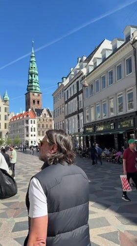 Pedestrians walk along geometric-tiled Copenhagen walkway