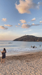 Golden hour at a Venezuelan beach, people and boats in the shallows