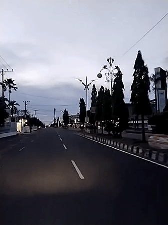 Motorcyclist travels empty road toward Lhokseumawe at dusk