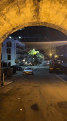 Rainy night street scene captured under archway in Portugal