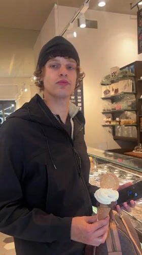 Young man enjoys gelato while using phone in Milan shop
