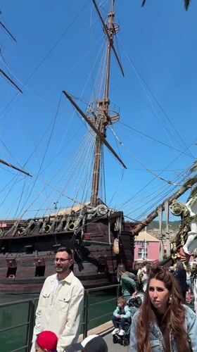 Sunny day at Genoa harbor features historic ship replica, aquarium fish
