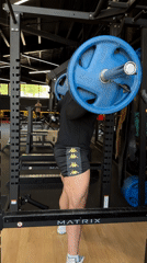 Man performs morning barbell squats in gym power rack
