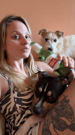 Woman enjoys beer with dogs in Tel Aviv apartment