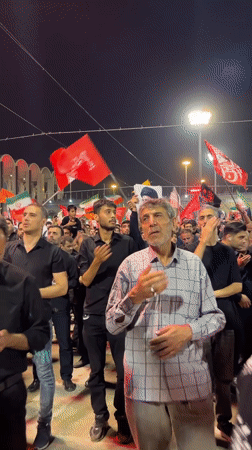 Red flags and solemn gestures at a Tehran night gathering