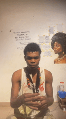 Paint-stained tank top and feathers, posing in Ado, Nigeria
