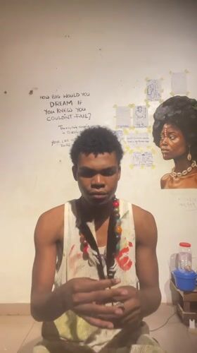 Paint-stained tank top and feathers, posing in Ado, Nigeria