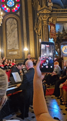 Red-robed choir performs with musicians in ornate Istanbul church