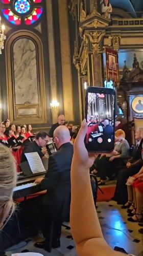 Red-robed choir performs with musicians in ornate Istanbul church