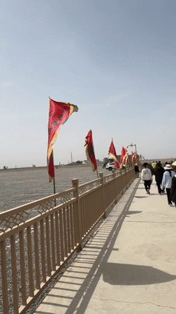 Red and yellow flags line pathway in Dunhuang