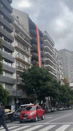 Rainbow banner displayed on Buenos Aires building amid street activity