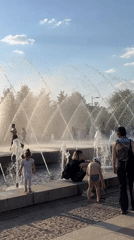 Girl in pink enjoys sunny day at Saint Petersburg fountain