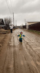 Children in snowsuits walk muddy roads in Chaikovsky, Russia