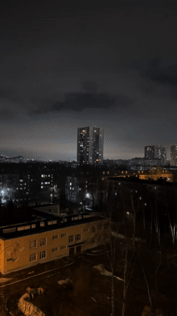 Woman in black robe observed in nighttime Kazan cityscape