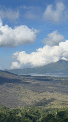 Video captures volcanic landscape with green vegetation under cloudy sky