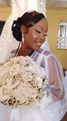 Bride in white dress poses with bouquet during wedding preparations