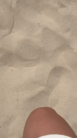 Person with red nail polish walks on Tel Aviv beach