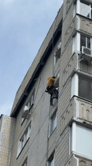 Woman photographs herself outdoors near residential building during morning