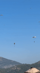 Paragliders over Fethiye as the beach fills up
