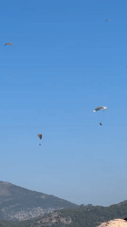 Paragliders over Fethiye as the beach fills up