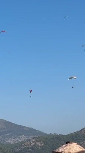 Paragliders over Fethiye as the beach fills up