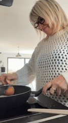 Woman prepares egg and noodle breakfast in French kitchen
