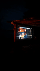 Casual riverside evening gathering with campfire and outdoor movie screening