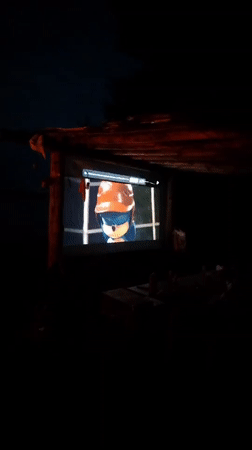 Casual riverside evening gathering with campfire and outdoor movie screening