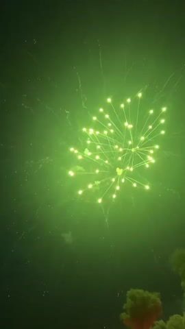This video captures a nighttime fireworks display. The first frame shows a large green fireworks burst against a dark sky, with smaller sparks trailing outwards. The second frame shows a single, thin streak of yellow light ascending diagonally against a black sky, with faint, blurry circular shapes also visible. The third frame displays two orange and yellow fireworks exploding in the dark sky. The fourth frame shows a vibrant orange fireworks burst with numerous radiating lines. The final frame features a cluster of small, golden fireworks explosions against a dark background, with a thin streak of golden light ascending from the bottom right corner.