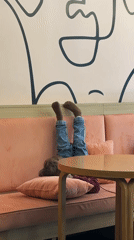 Child rests playfully on cafe sofa in Novi Sad