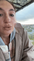 Woman photographs herself on Sochi balcony overlooking city skyline
