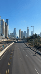 Empty Tel Aviv roads: one cyclist, one car, clear skies
