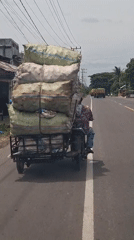 Motorcyclist transports sacks through Indonesian villages via sidecar, trailer