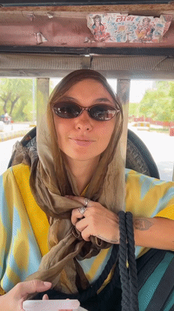 Woman in headscarf rides tuk-tuk on tree-lined Vrindavan street