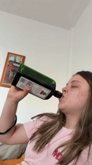 Woman drinks from bottle, balances cup in Spanish coastal town