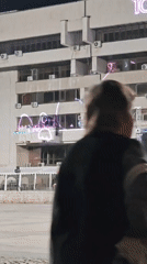 Evening plaza scene with building projection and street life
