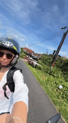 Woman on motorcycle smiles while riding through Pupuan, Indonesia