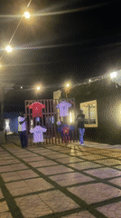 Evening patrons gather at illuminated Nigerian bar patio