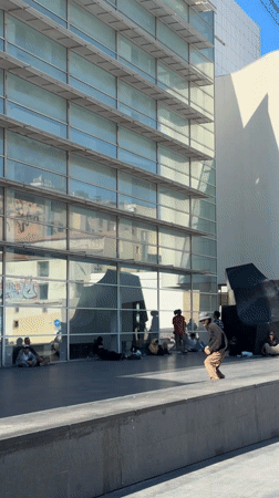 Skateboarder performs tricks near Barcelona's Torre Glòries building
