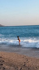 Children play on Fethiye beach amid paragliding activity