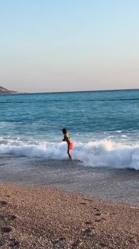 Children play on Fethiye beach amid paragliding activity